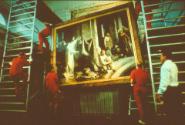 N - Art Handlers continue to lower the Bloch painting while being observed by Conservator in wh…