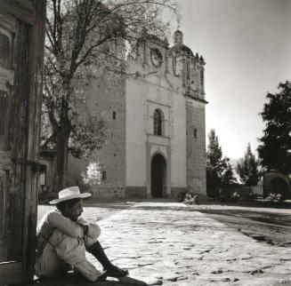 HOMBRE SENTADO EN EL ATRIO DE UNA IGLESIA