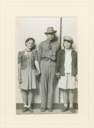 STANDING MAN IN HAND FLANKED BY TWO WOMEN, HOLDING HANDS, STRIPED BACKGROUND