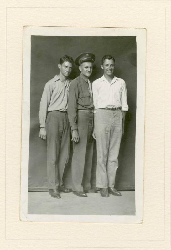 THREE STANDING MEN, ONE WITH MILITARY CAP