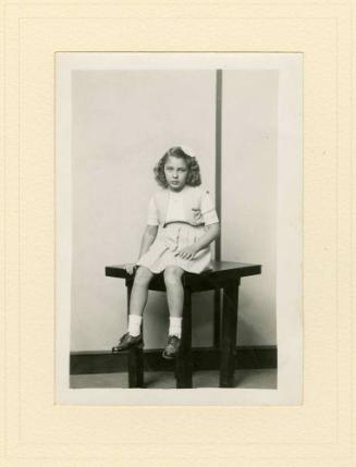 SEATED GIRL ON TABLE, STRIPED BACKGROUND